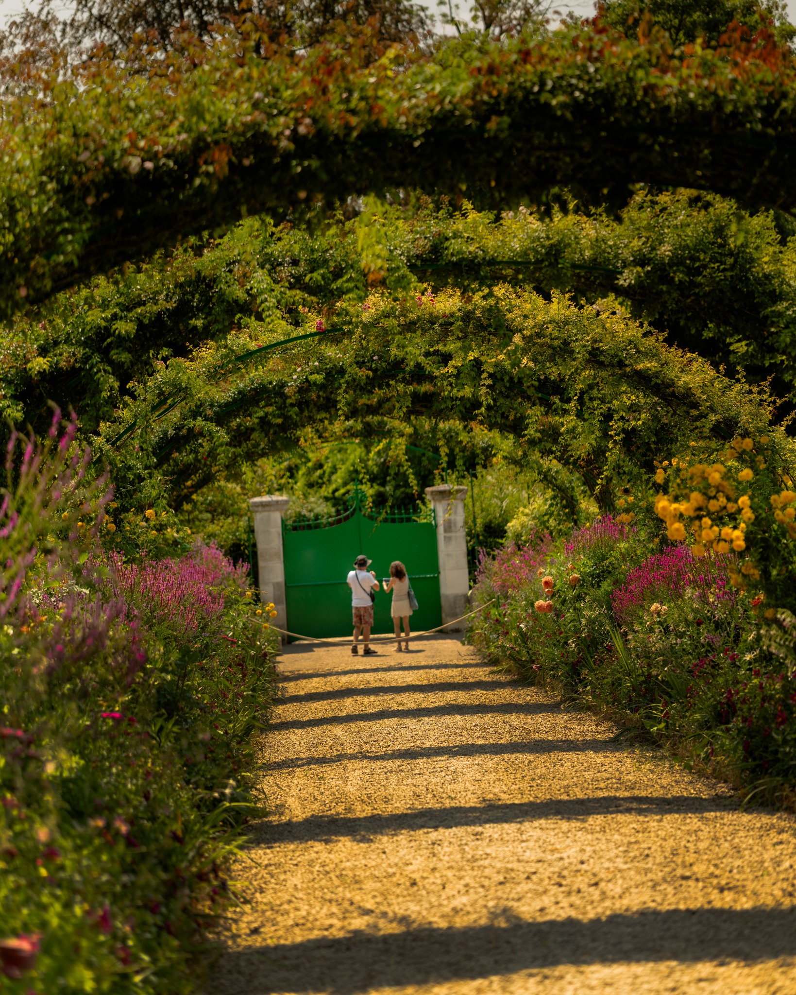 Two visitors walking through a flower-lined garden path