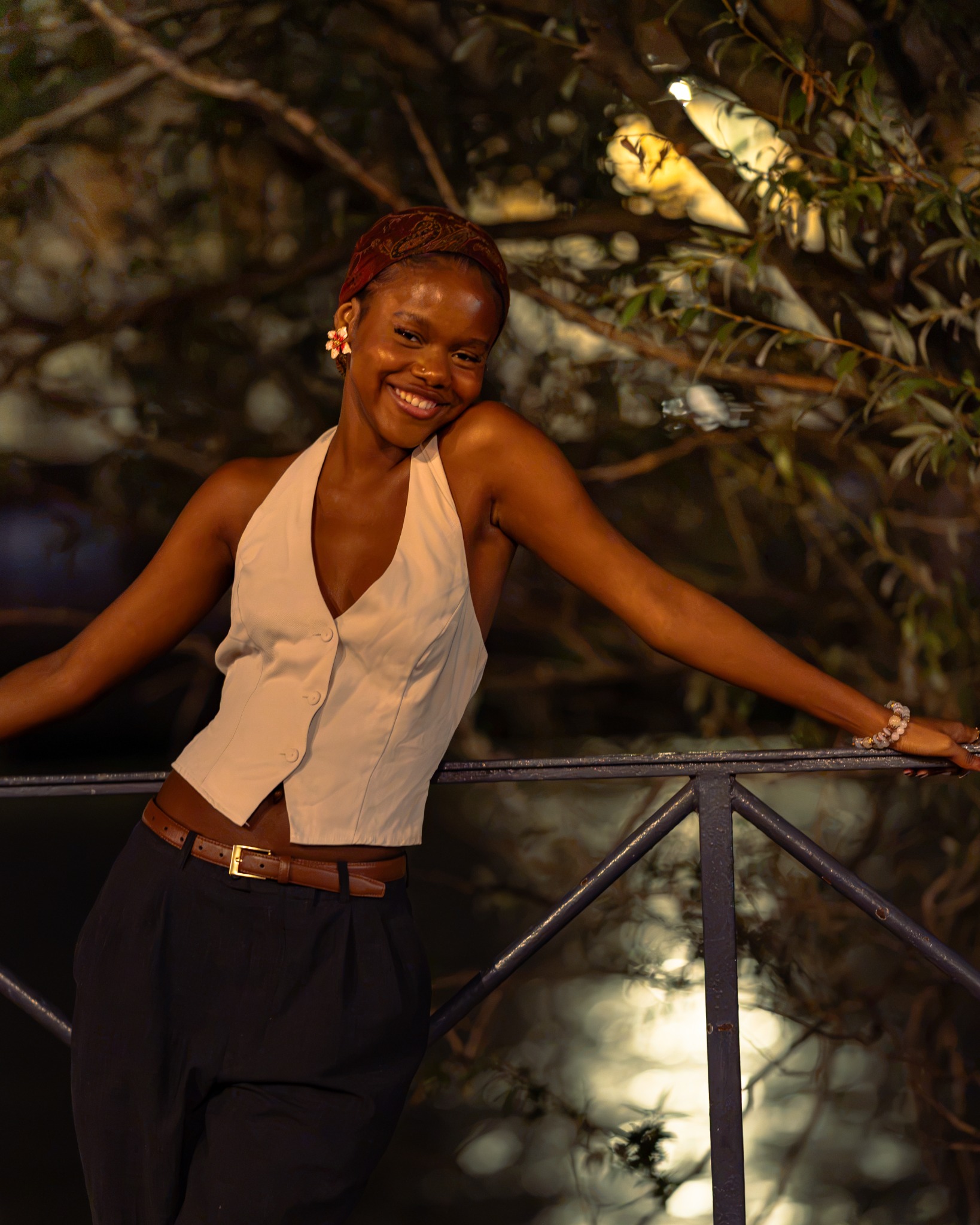 Smiling woman leaning against a railing beneath warm lights